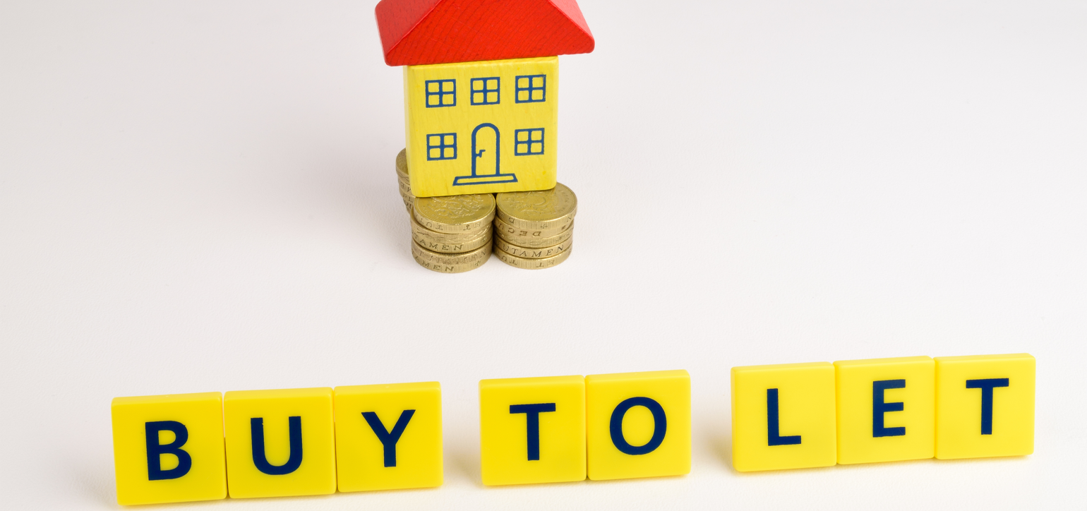 Image of a model house sitting on some coins with the words “Buy to let” in front