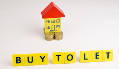 Image of a model house sitting on some coins with the words “Buy to let” in front