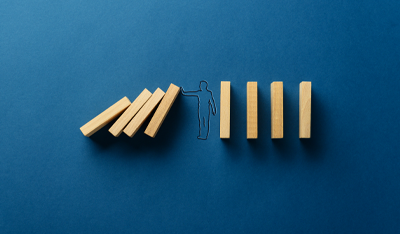Graphic of a line drawn man standing in between some tall blocks, stopping them from knocking some others down