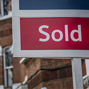 Image showing a "Sold" sign in front of a row of houses
