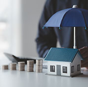 Image showing a row of coins next to a model house covered by an umbrella