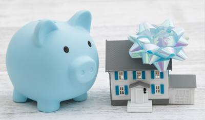 Inheritance a house with a blue piggy bank with a bow on a wood desk