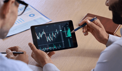 Trader consulting business investor showing crypto trading chart using digital tablet. Over shoulder view