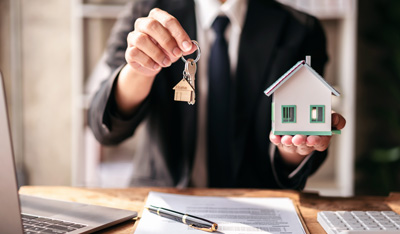 Image Showing a a man holding keys and wood houses in hand