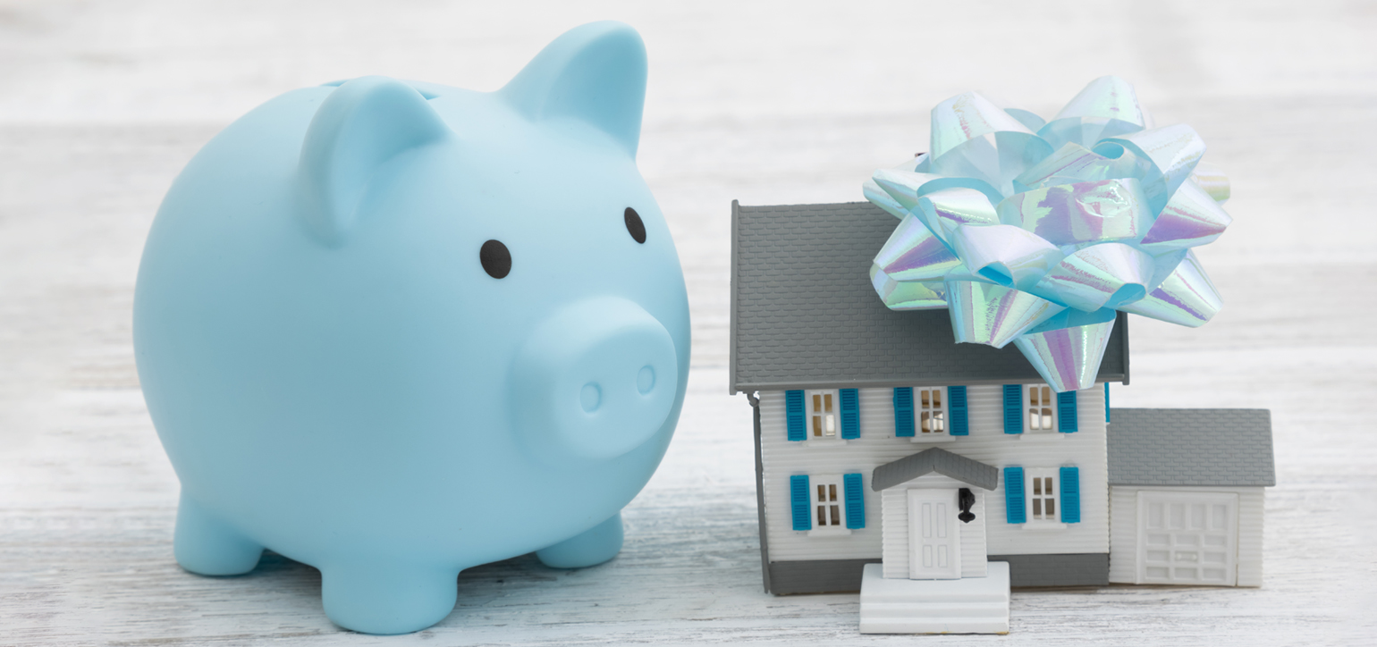 Inheritance a house with a blue piggy bank with a bow on a wood desk